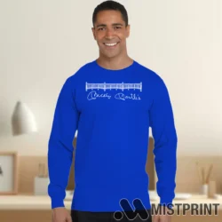 Male Model Wearing 80s Mickey Mantles Signature NYC Restaurant Graphic New York Yankees Team Legend Men's Royal Blue Long Sleeve in a minimalist gray office background. Styled with a casual long sleeve top.